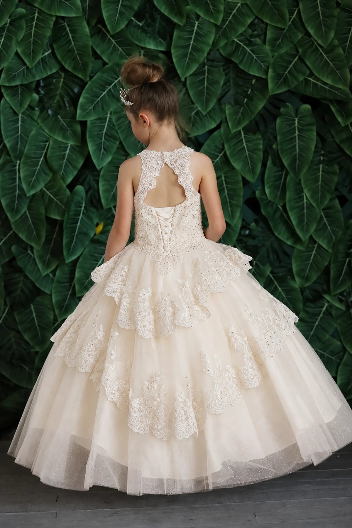 Turning to the back, the Champagne mini quince dress displays its lace-up finish and full layered tulle skirt with ruffle tiers.