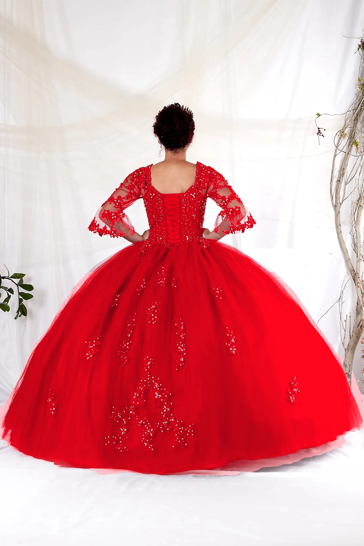 Back view of the Red quinceañera ball gown showing the lace-up bodice, embroidered sheer sleeves and voluminous skirt.