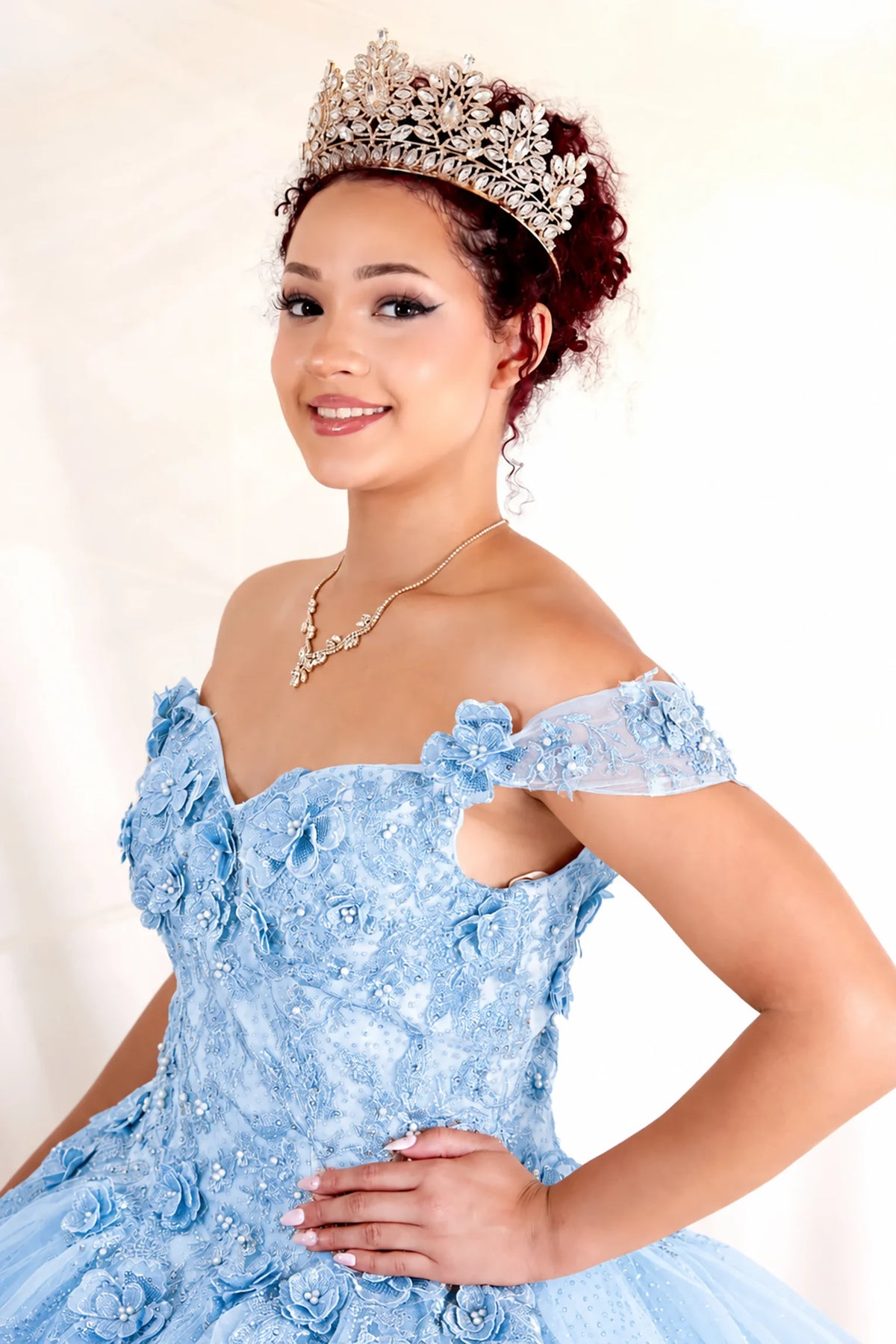 Dimensional floral appliqués and glitter accents defines the Bahama Blue quinceañera dress in this detailed view.