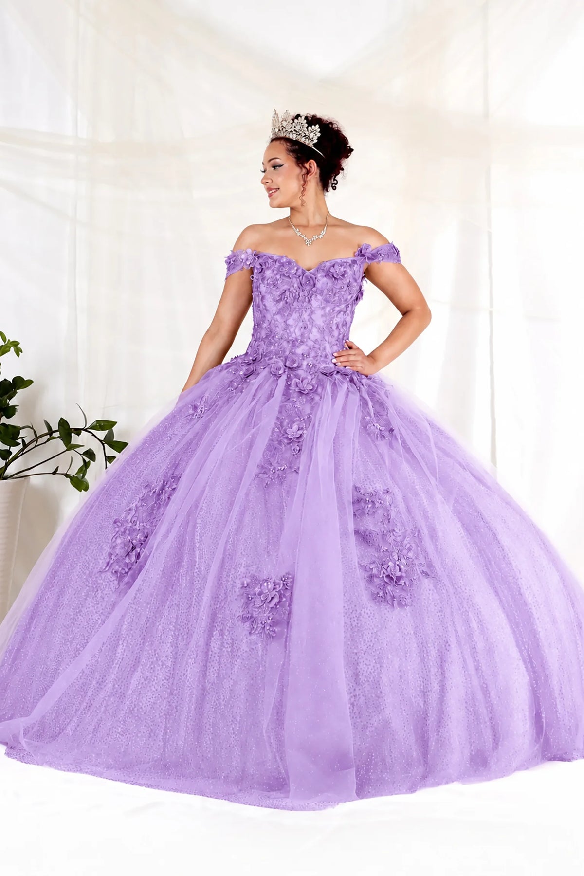 Lilac quinceañera dress showcases dimensional floral appliqués and glitter accents above full tulle ball gown skirt.
