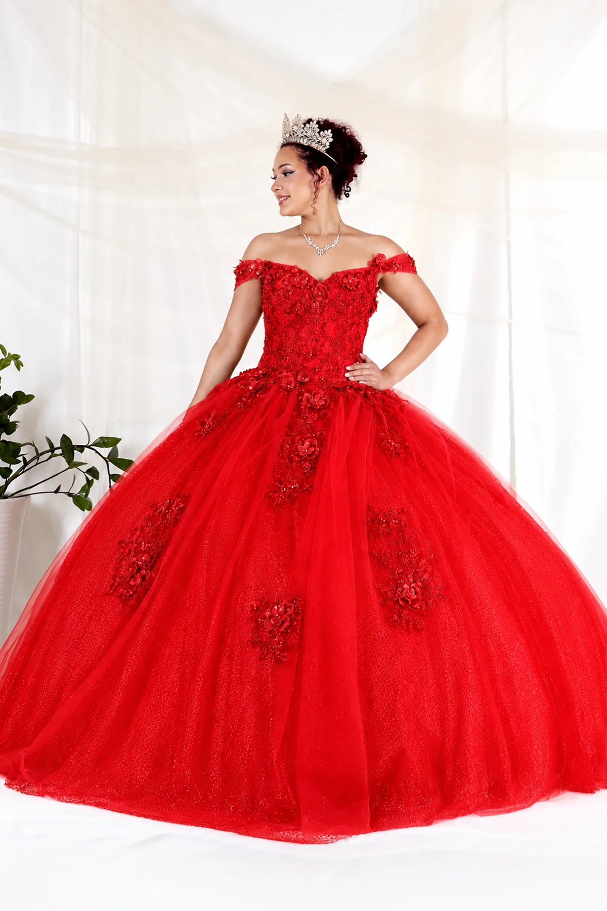 Red quinceañera dress showcases dimensional floral appliqués and glitter accents above full tulle ball gown skirt.