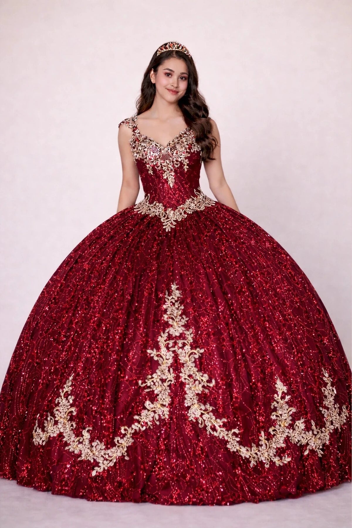 Burgundy quinceañera dress showcases metallic embroidered scrollwork above sparkling full ball gown silhouette.
