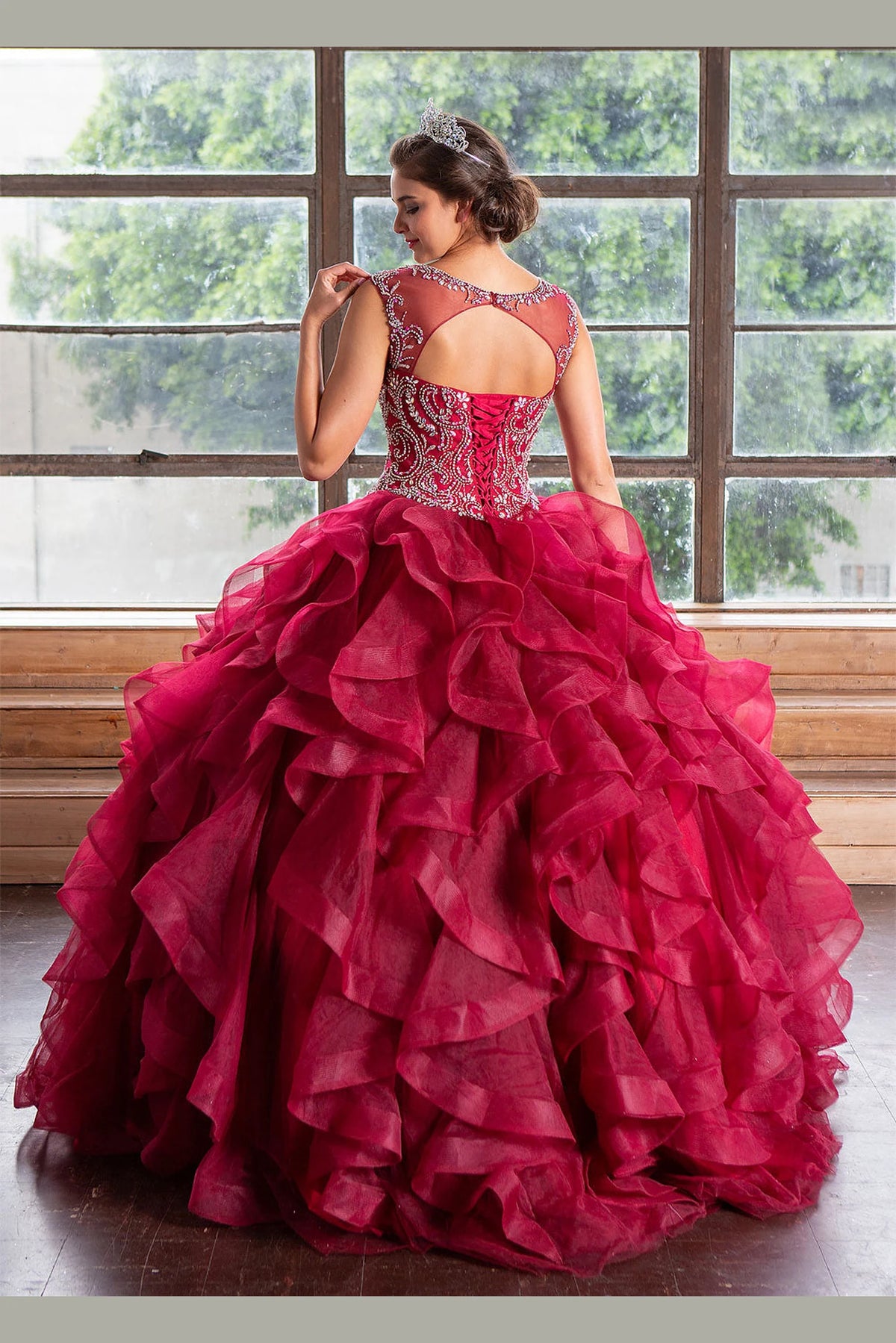 From behind, the Burgundy quinceañera ball gown reveals a fitted back and the dimensional finish of the skirt.