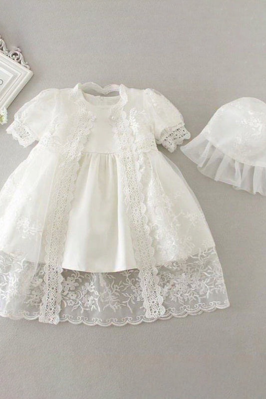 White lace baby dress with matching hat on a gray background