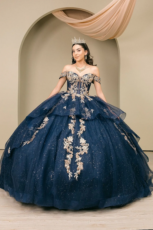 Woman wearing navy quinceañera dress with gold embroidered corset bodice, tiered shimmer tulle skirt, extended train, and detachable cape layer