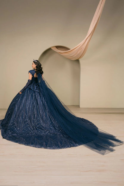 Woman wearing navy quinceañera royal dress three-quarter view with ornate beaded corset bodice, shimmering textured skirt, cathedral train, detachable cape, choker neckline, and gloves
