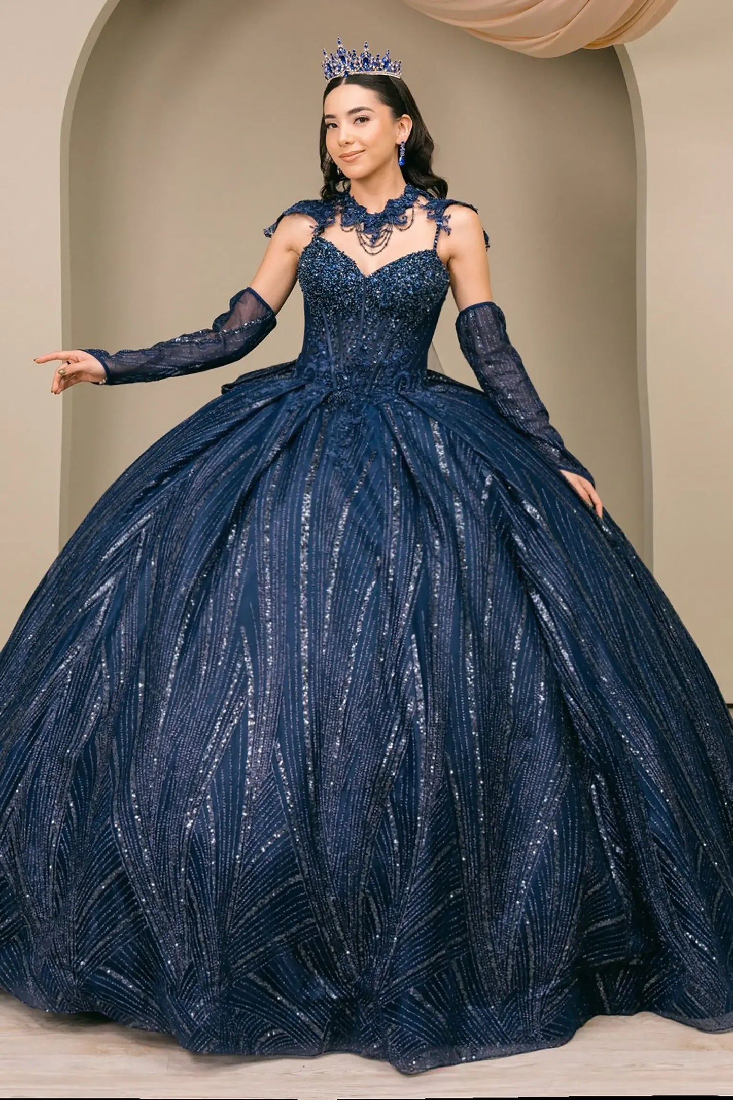 Woman wearing navy quinceañera royal dress with beaded corset bodice, shimmering textured skirt, cathedral train, choker neckline, detachable cape, and gloves