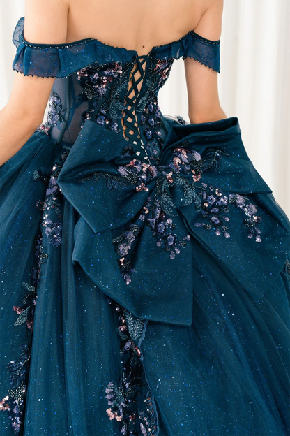 Close-up of woman back-facing in navy quinceañera royal dress with lace-up beaded corset bodice, detachable cape, shimmering textured skirt, cathedral train, and gloves