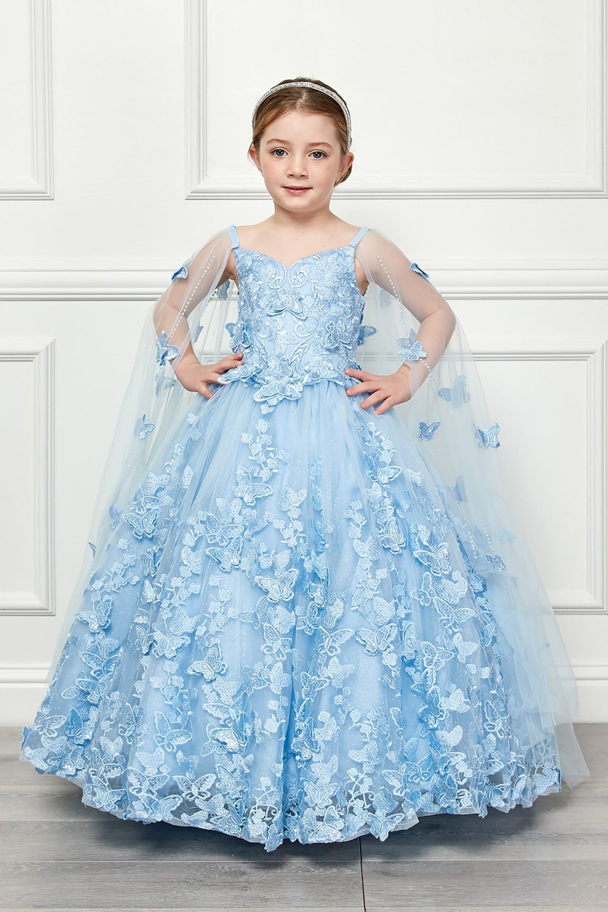 Front view of a blue kids mini quinceanera mini quince dress with 3D butterfly floral appliques, off-shoulder neckline, and detachable cape.