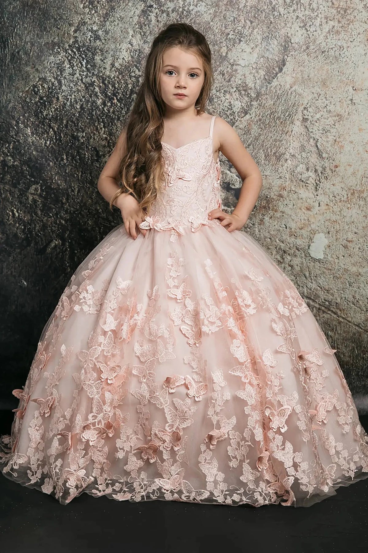 Front view of a blush kids mini quinceanera mini quince dress with 3D butterfly floral appliques, off-shoulder neckline, and flowing cape.