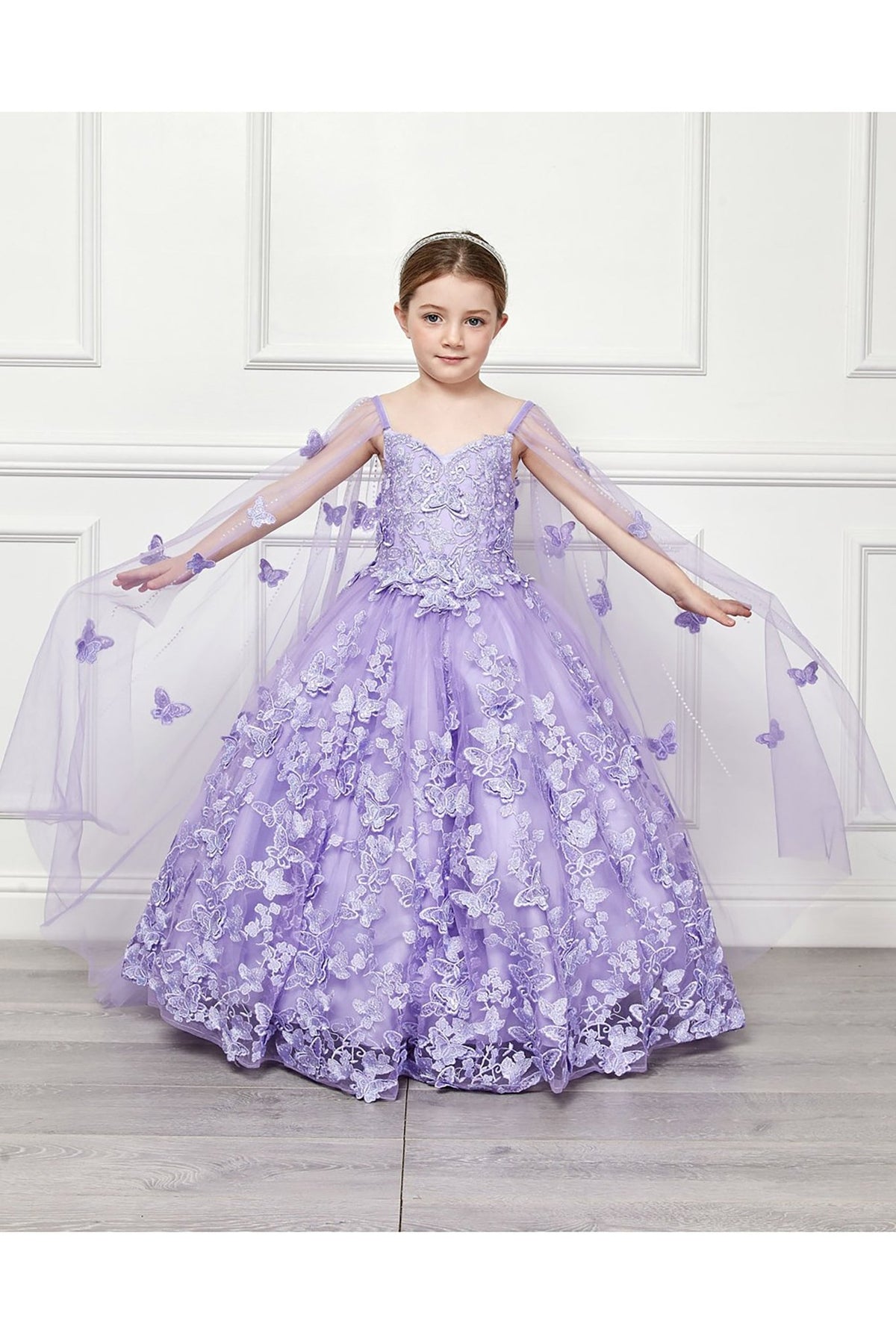 Front view of a lilac kids mini quinceanera mini quince dress with 3D butterfly floral appliques, off-shoulder neckline and flowing cape.