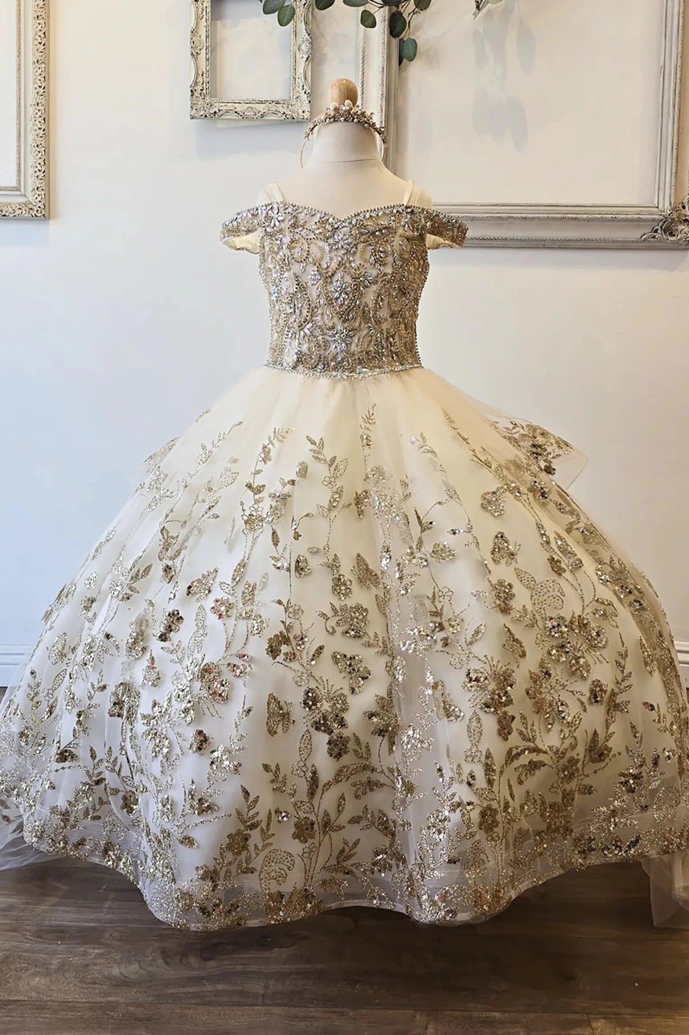Front view of an ivory champagne kids mini quinceanera mini quince dress with gem-embellished bodice, glitter tulle skirt, and detachable train.