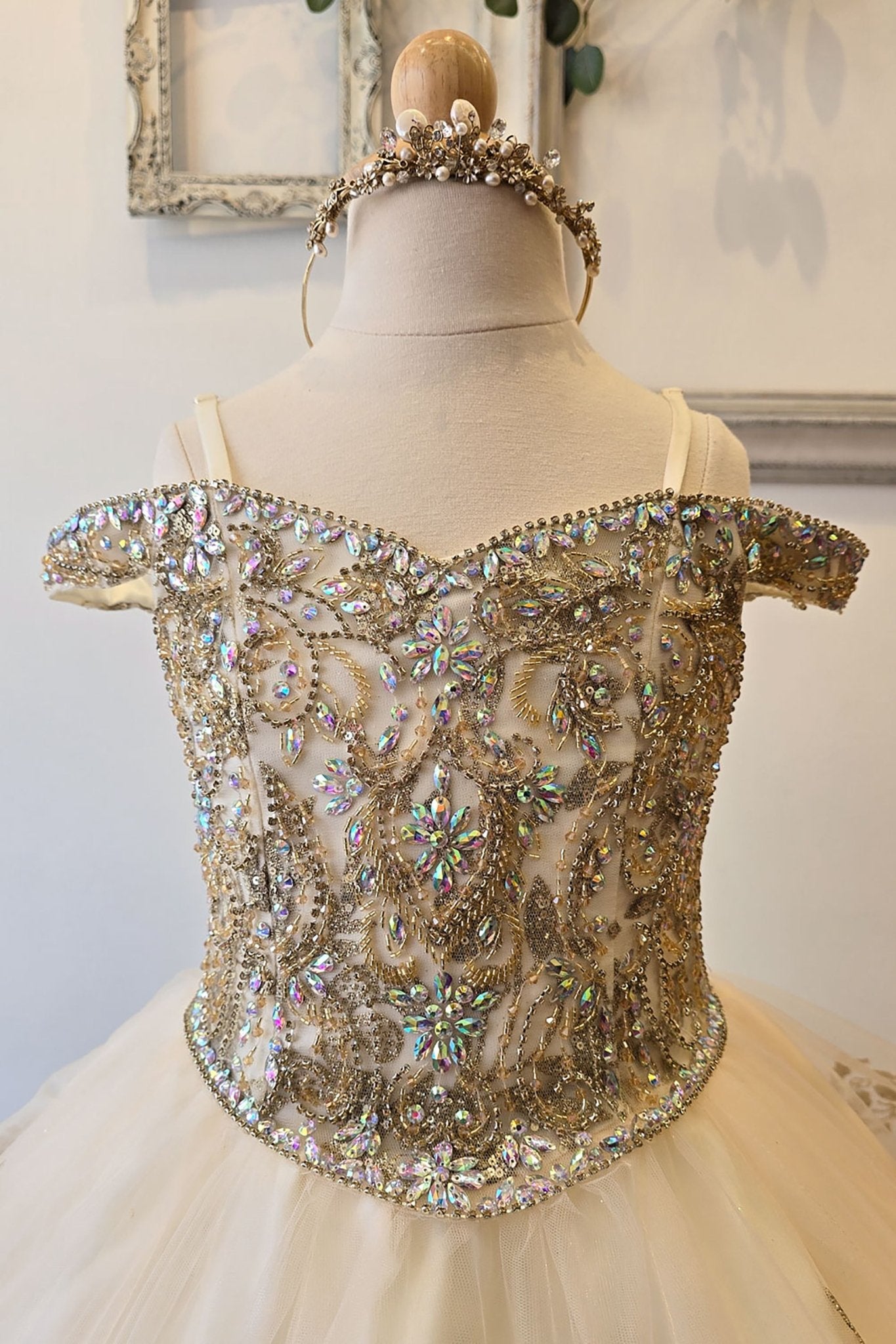 Zoomed front view of an ivory champagne kids mini quinceanera mini quince dress highlighting gem-embellished bodice, floral detailing, and glitter tulle skirt.