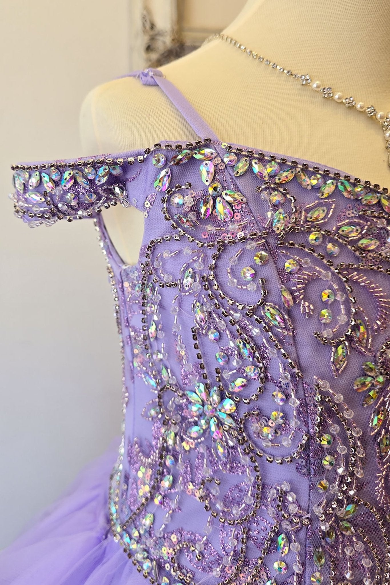 Side close-up of a lilac kids mini quinceanera mini quince dress showing gem-embellished bodice, puffed sleeve detail, and glitter tulle fabric.