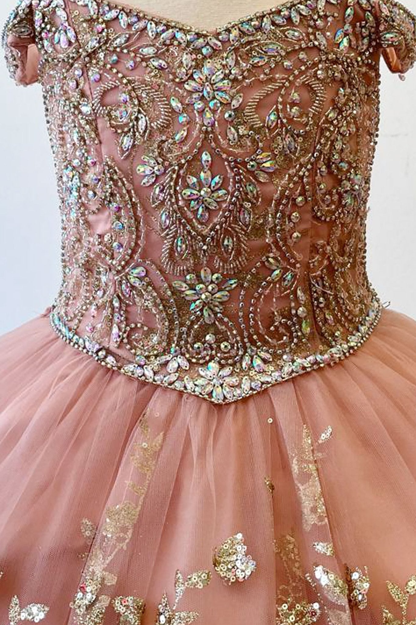 Zoomed front view of a rose gold kids mini quinceanera mini quince dress highlighting gem-embellished bodice, floral detailing, and glitter tulle skirt.