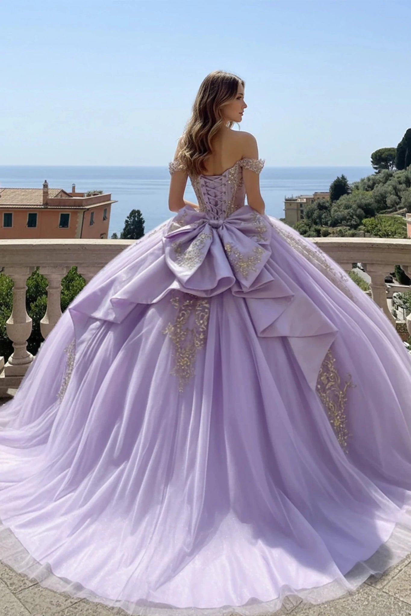 Lavender ball gown with a large bow and gold accents in an outdoor setting.