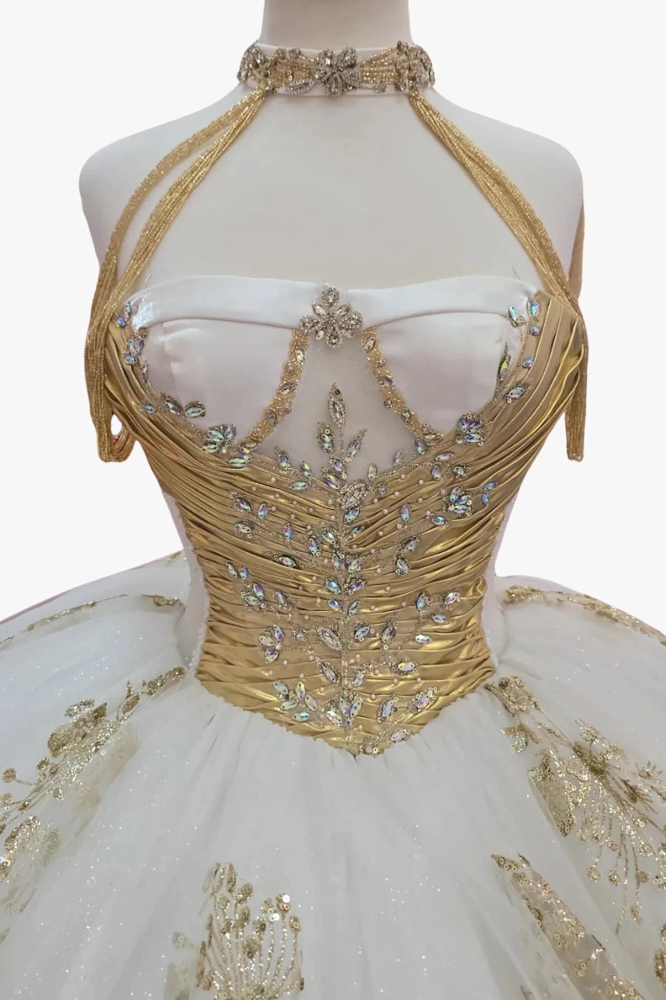 white ball gown with intricate detailing such as beautiful ab color stones with gold embroidery on a mannequin.