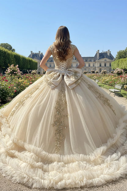 Woman in a champagne quince ball gown showing her back of the dress with large bow and long train 