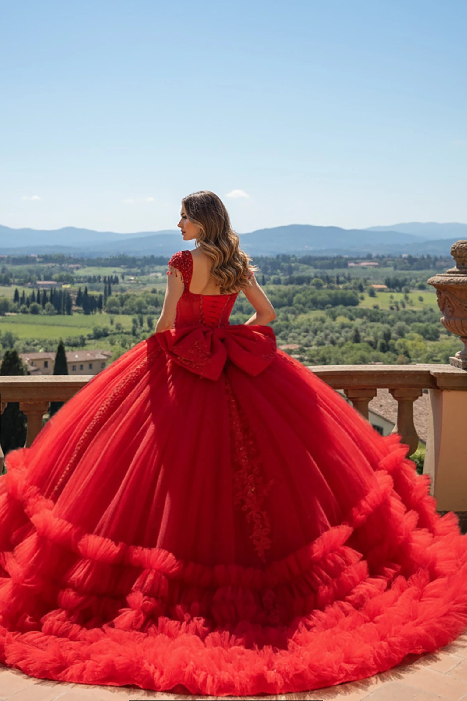 Woman in a red ball gown with ruffled hem and big bow and long train