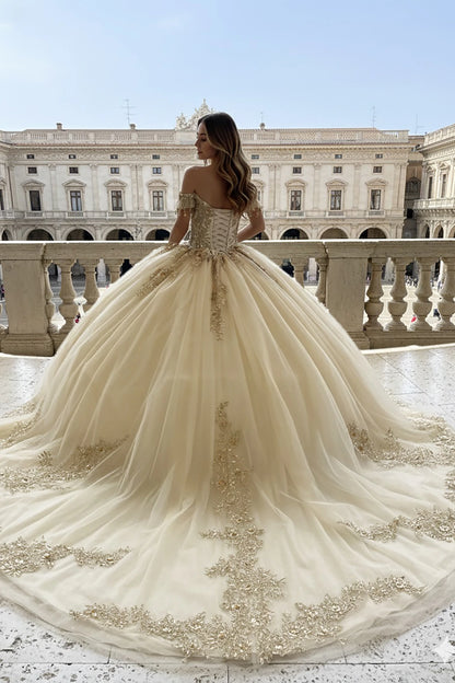 Woman in a champagne quinceanera dress with gold embroidery and long train 