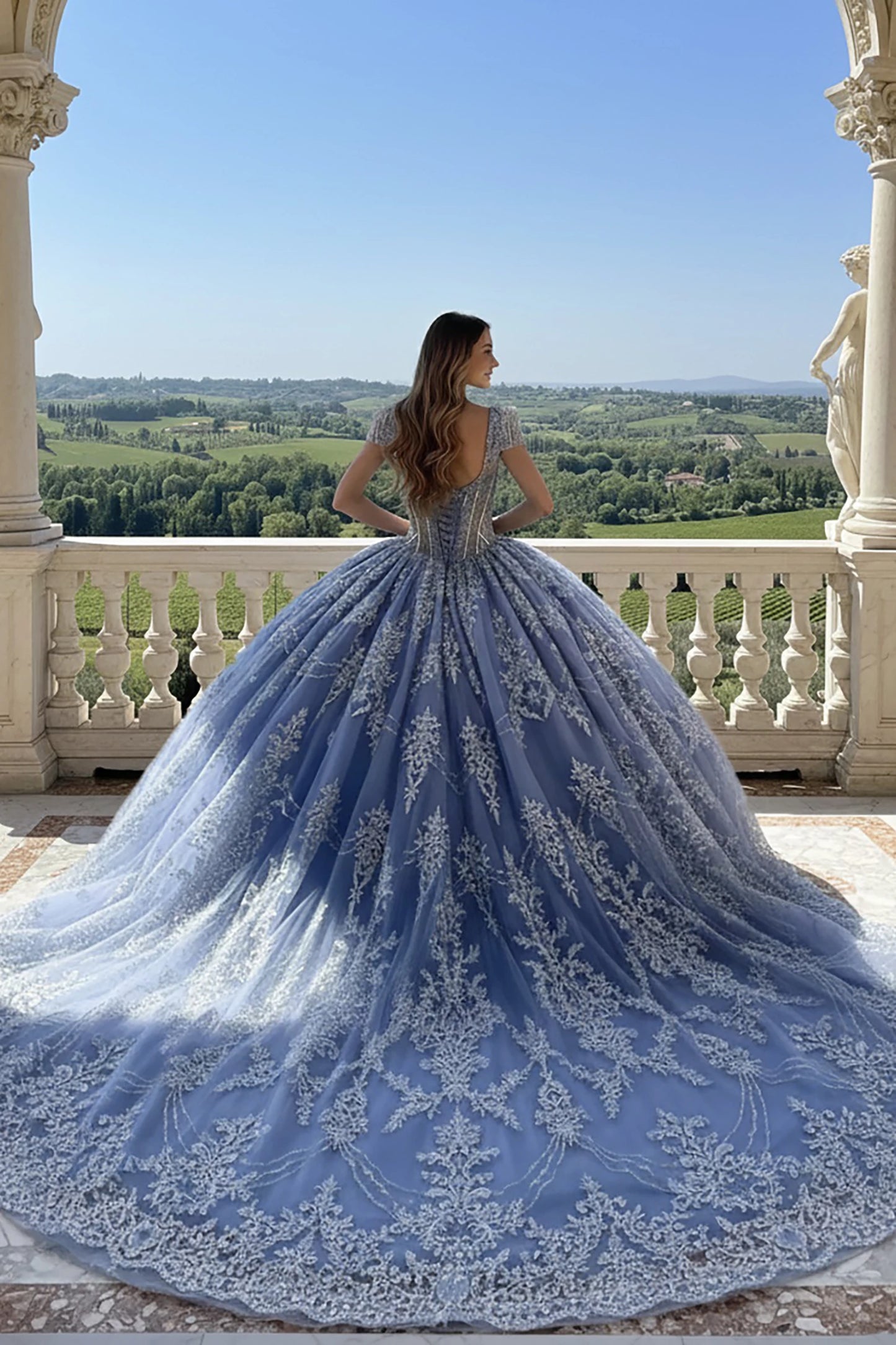 Woman in a blue lace ball gown dress with long train showing her back 
