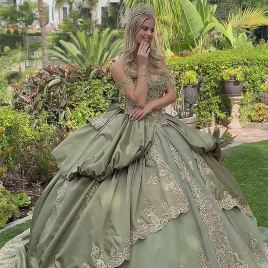 a girl wearing sage satin quince dress and tiara showing her back in a green garden. video