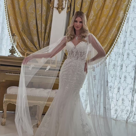 video of the wedding dress; a girl wearing a trumpet style dress and there is small train near her shoulder to the ground and it looks like a long sleeves too.