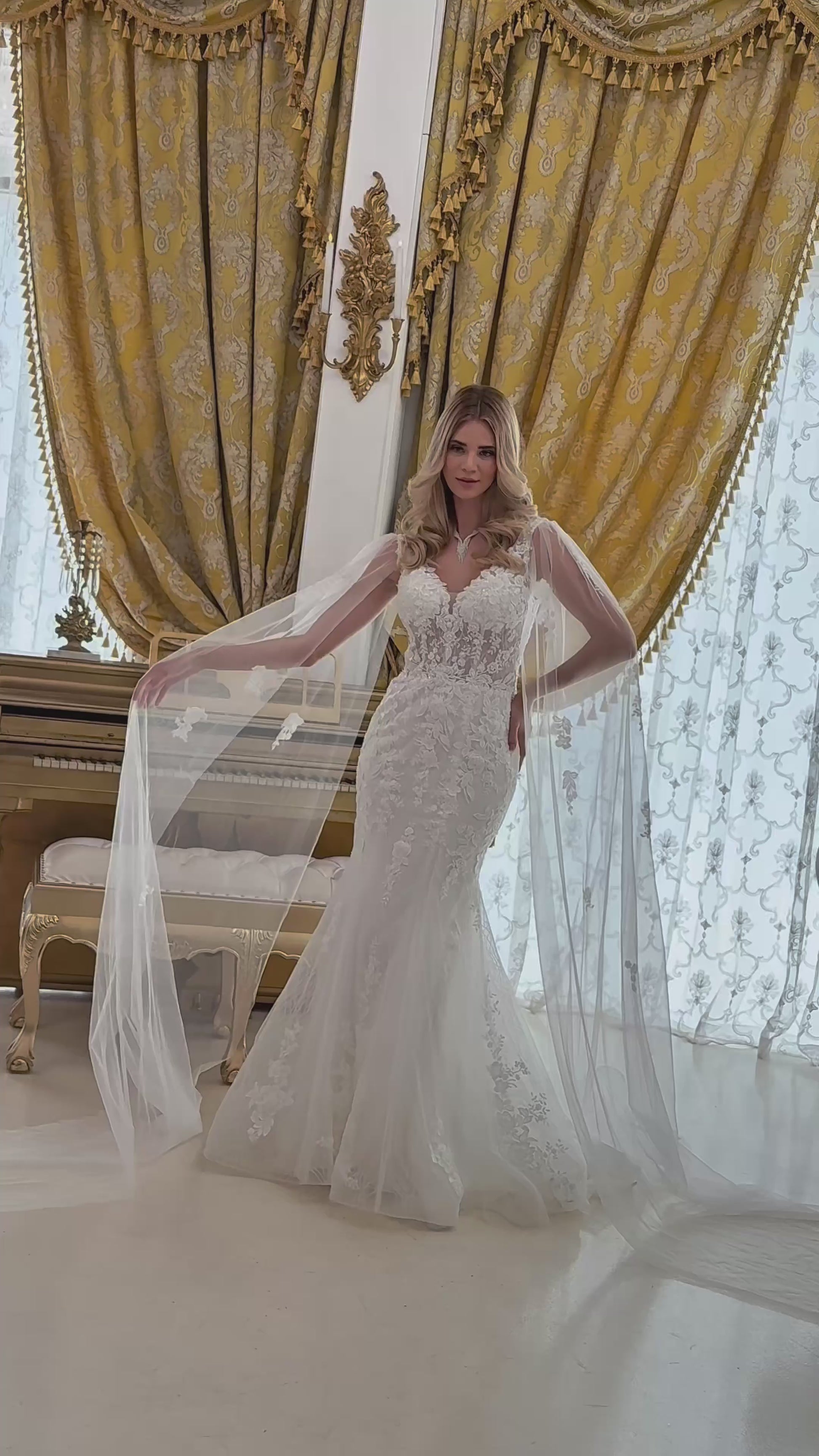 video of the wedding dress; a girl wearing a trumpet style dress and there is small train near her shoulder to the ground and it looks like a long sleeves too.