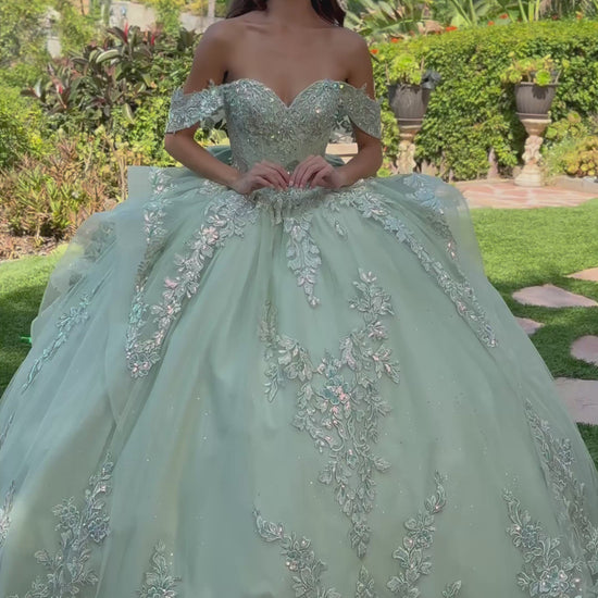 girl in a sage quinceañera dress with floral details standing outdoors. video