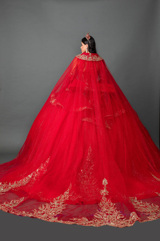 Woman back-facing in red off-shoulder ball gown quinceañera dress with lace-up corset bodice, ornate appliqué, detachable hooded cape, and cascading tulle skirt