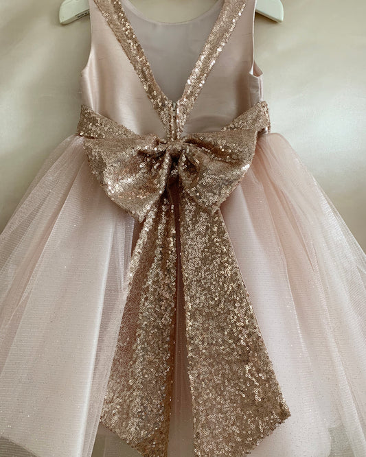 Pink dress with a large sequin bow on a mannequin against a neutral background