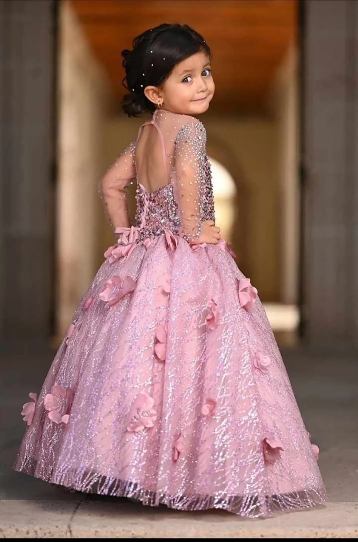 Seen at full length, the Dusty Rose mini quince dress showcases sheer long-sleeve bodice with three-dimensional flowers and embroidered tulle skirt with a lace-up back.