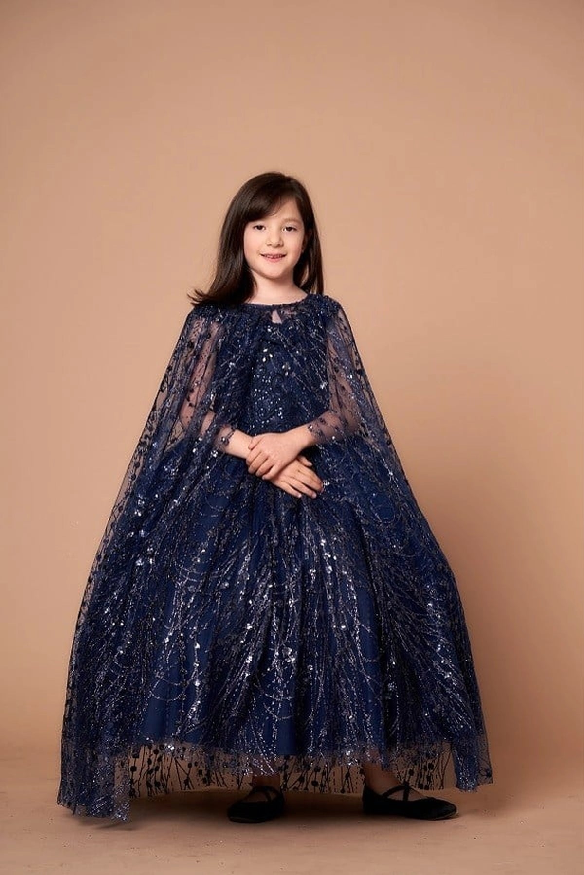 Sparkling details shape, the Navy mini quince dress showcases off-the-shoulder bodice with allover sequins and glitter and matching cape over a full sparkling skirt.
