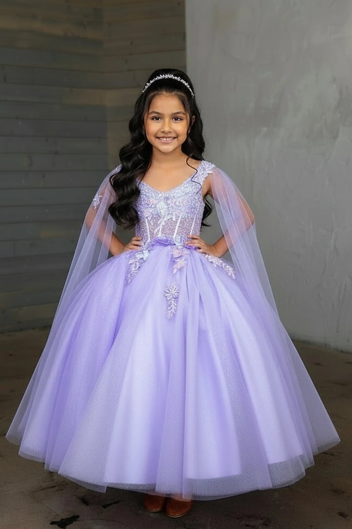 A closer look shows, the Lilac mini quince dress showcases sheer flowing cape sleeves and floral embroidered bodice and full tulle skirt.