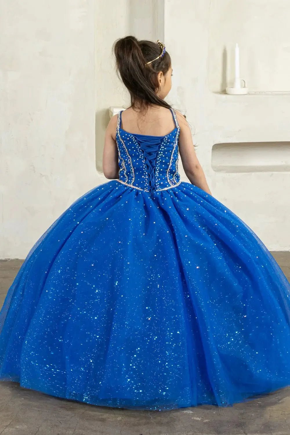 Back view of royal blue mini quince dress with lace-up closure, 3D floral appliqué accents, glitter tulle, and cascading layered skirt.