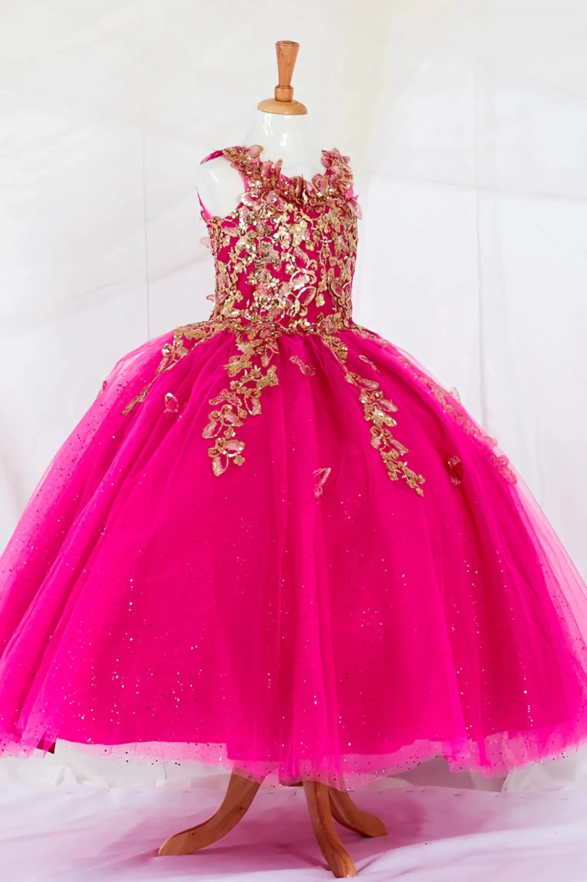 Side-facing in stunning fuchsia mini quince dress with 3D floral appliqué bodice and glitter tulle layered skirt.
