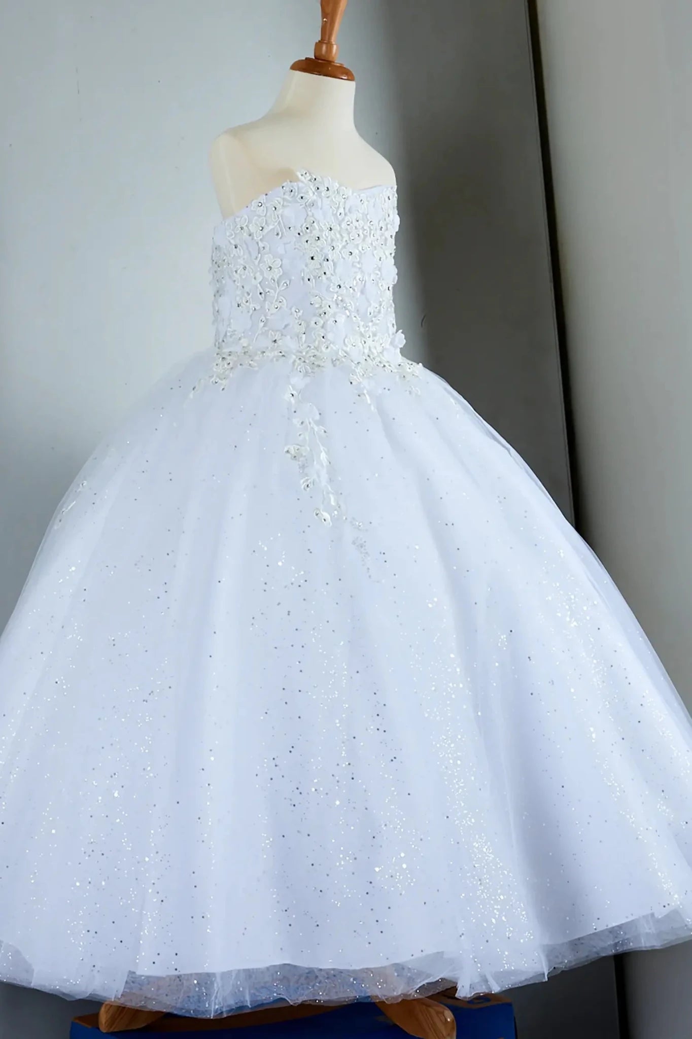 Side-facing in stunning blush pink mini quince dress with 3D flower appliqué bodice and glitter tulle layered skirt.