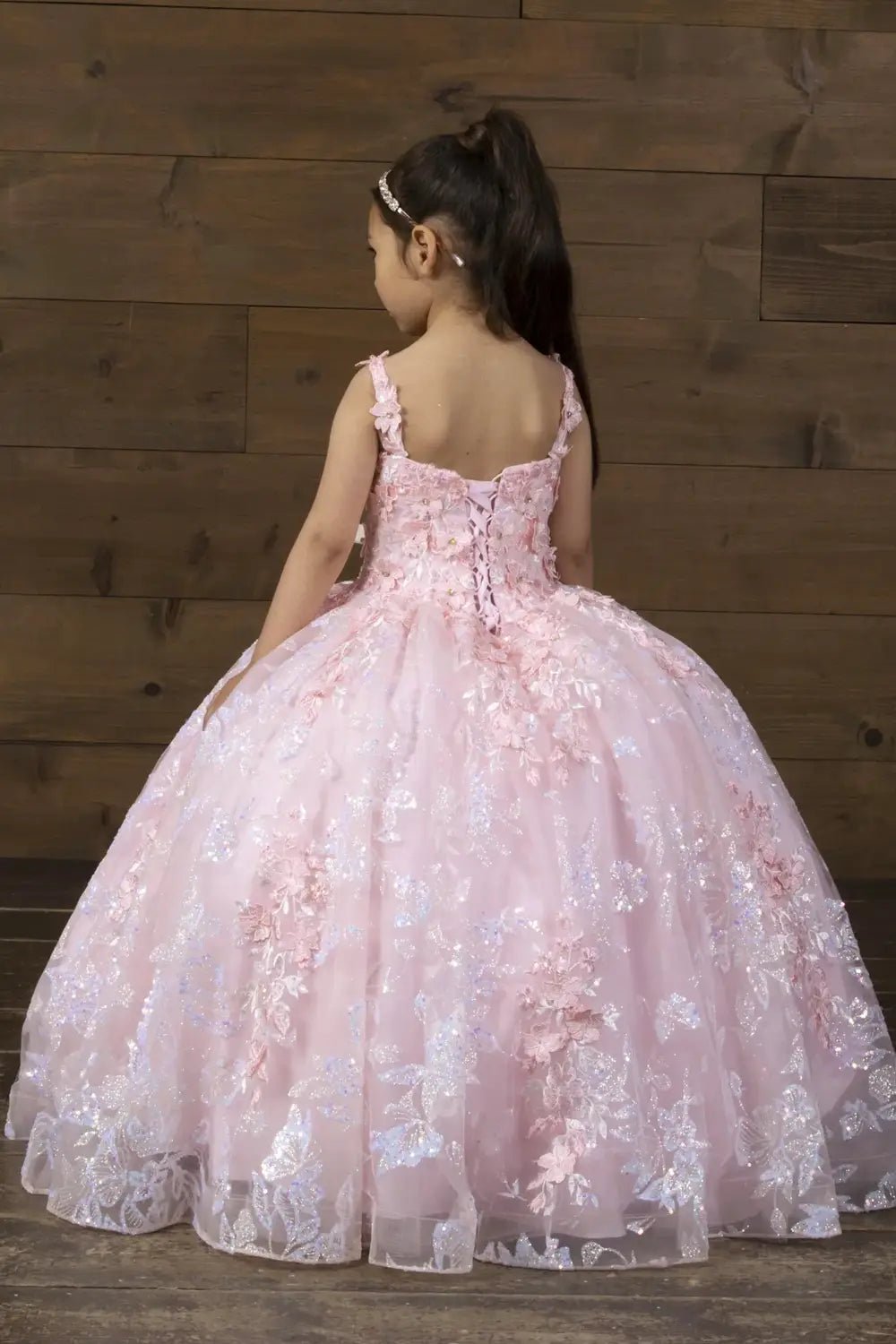 Back view of blush and gold mini quince dress with lace-up closure, butterfly accents, 3D floral appliqué, glitter tulle, and cascading layered skirt.