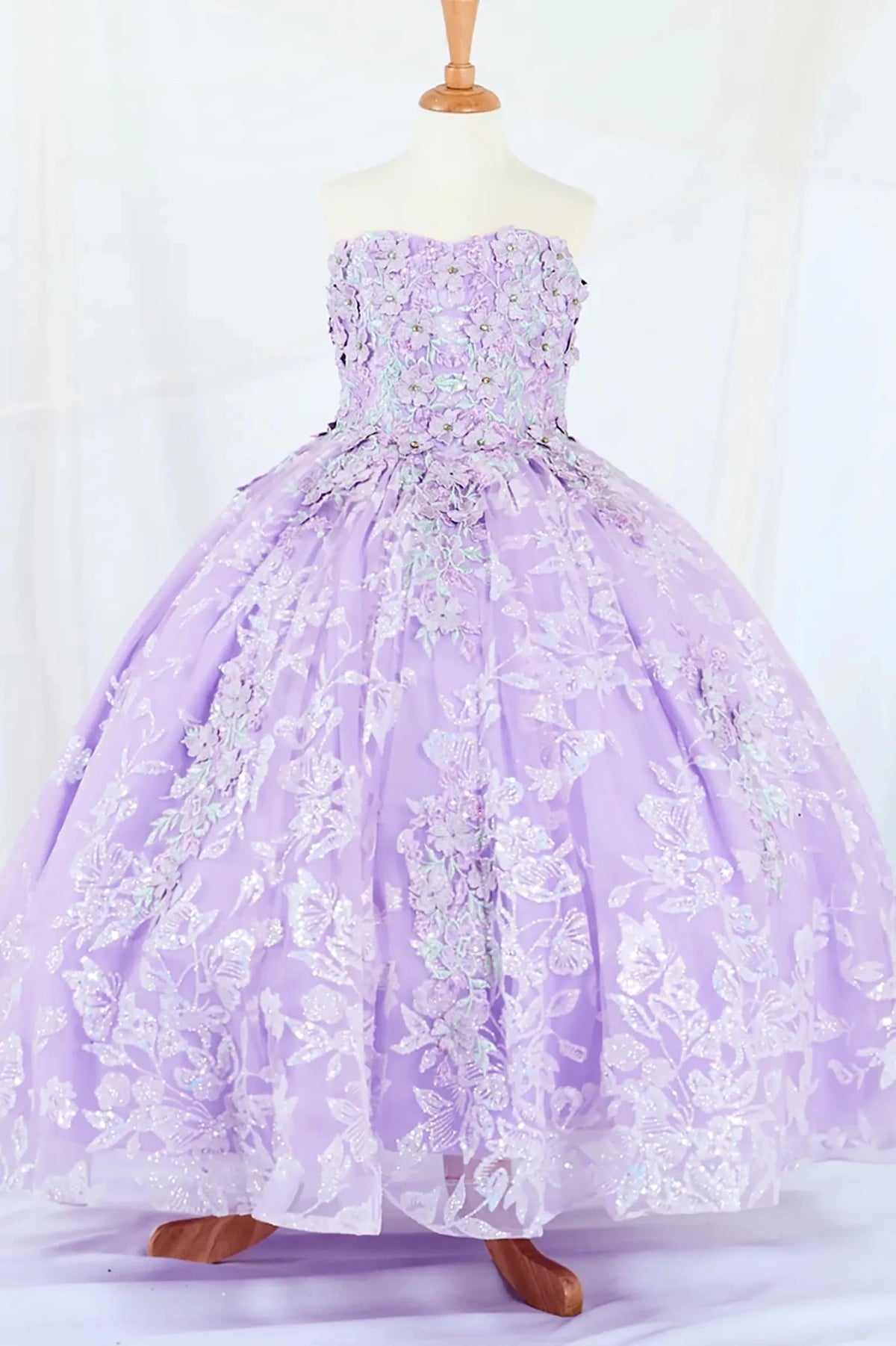 Front-facing display of a lilac mini quince dress featuring a 3D floral appliqué bodice with butterfly accents and a glitter tulle layered skirt.