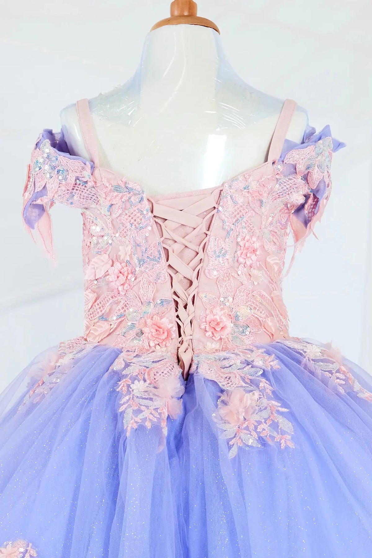 Close-up display highlighting the intricate glitter embroidery on the bodice and the delicate beadwork on the sleeves. Mini quince dress.