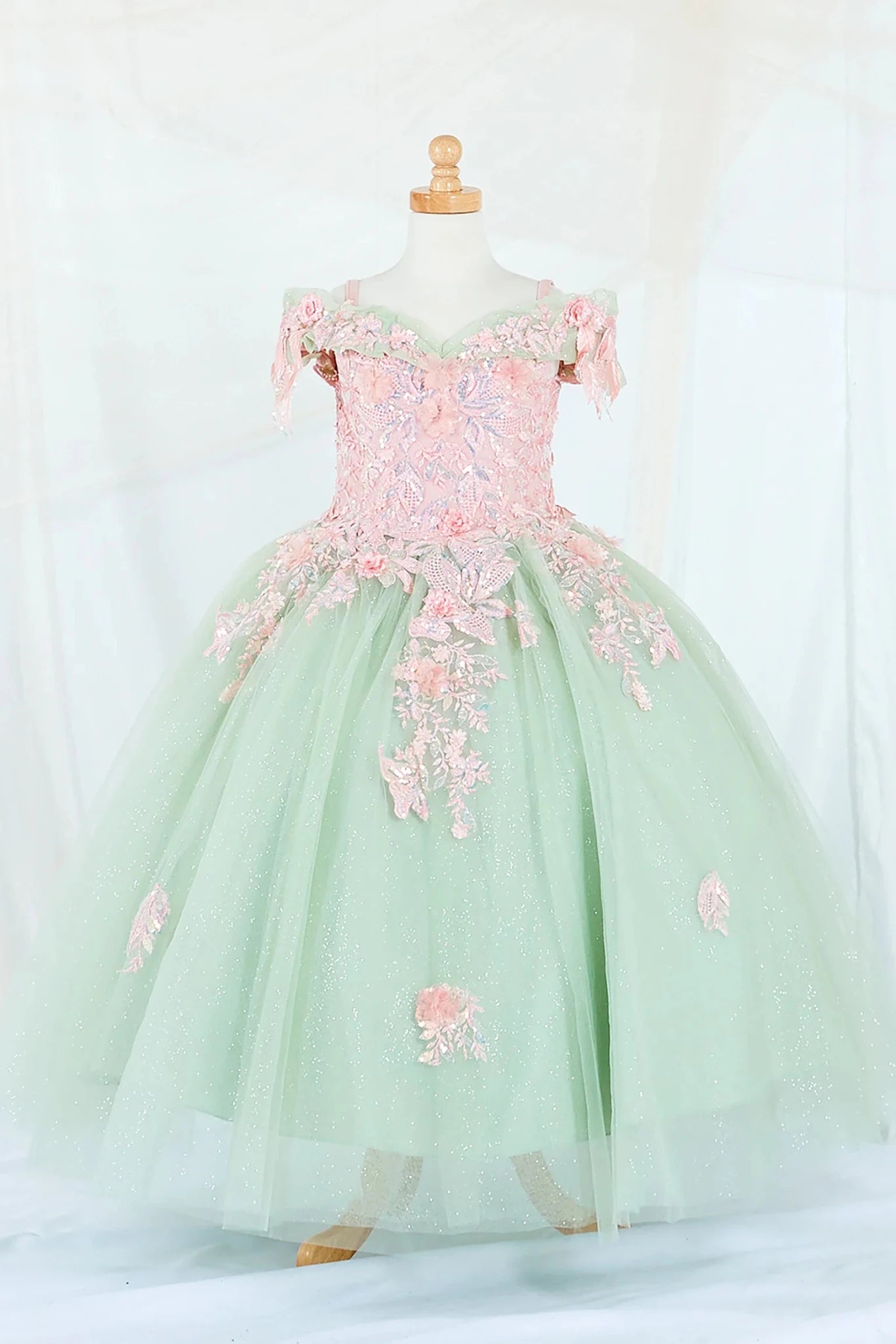 Front-facing display of an elegant sage and blush mini quince dress featuring a fitted bodice, detachable bow accent, and a glitter tulle layered skirt.