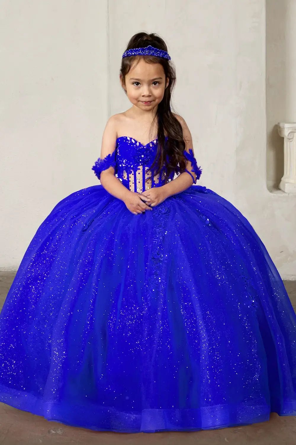 Front view of elegant royal blue mini quince dress with crystal beaded bodice, detachable bow accent, and glitter tulle layered skirt.