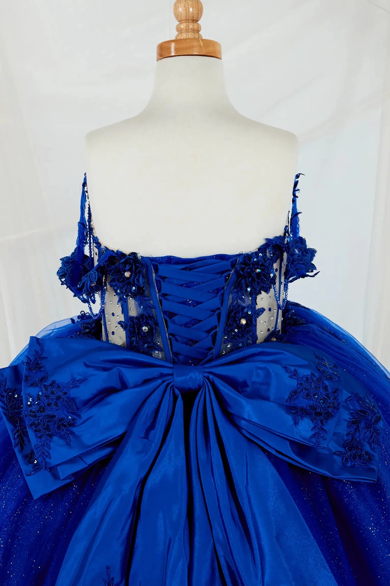 Close-up display highlighting the intricate crystal beadwork on the bodice and the detailed bow accent. Mini quince dress.