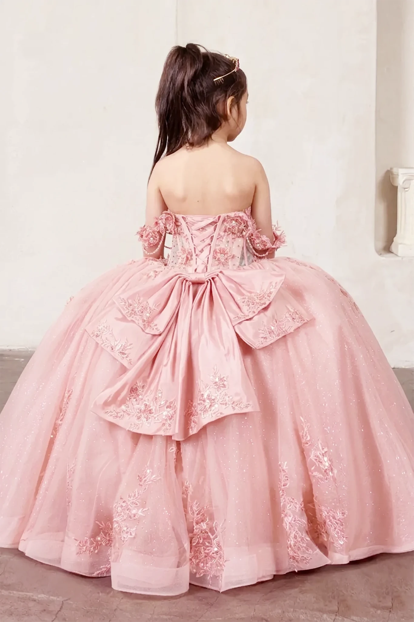 A pink formal mini quince dress with floral details and extra large back bow.