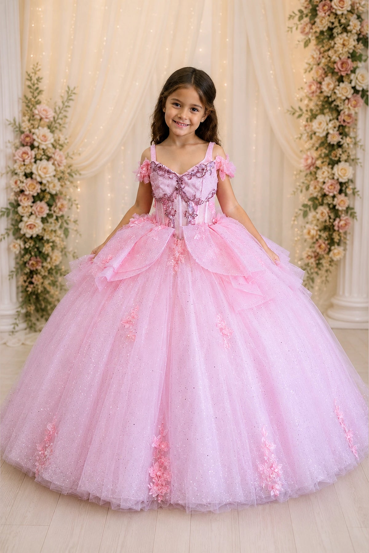 The dress profile reveals, the Bubble Pink mini quince dress showcases ruffled off-the-shoulder neckline and floral appliqués over a full tulle ball gown skirt.