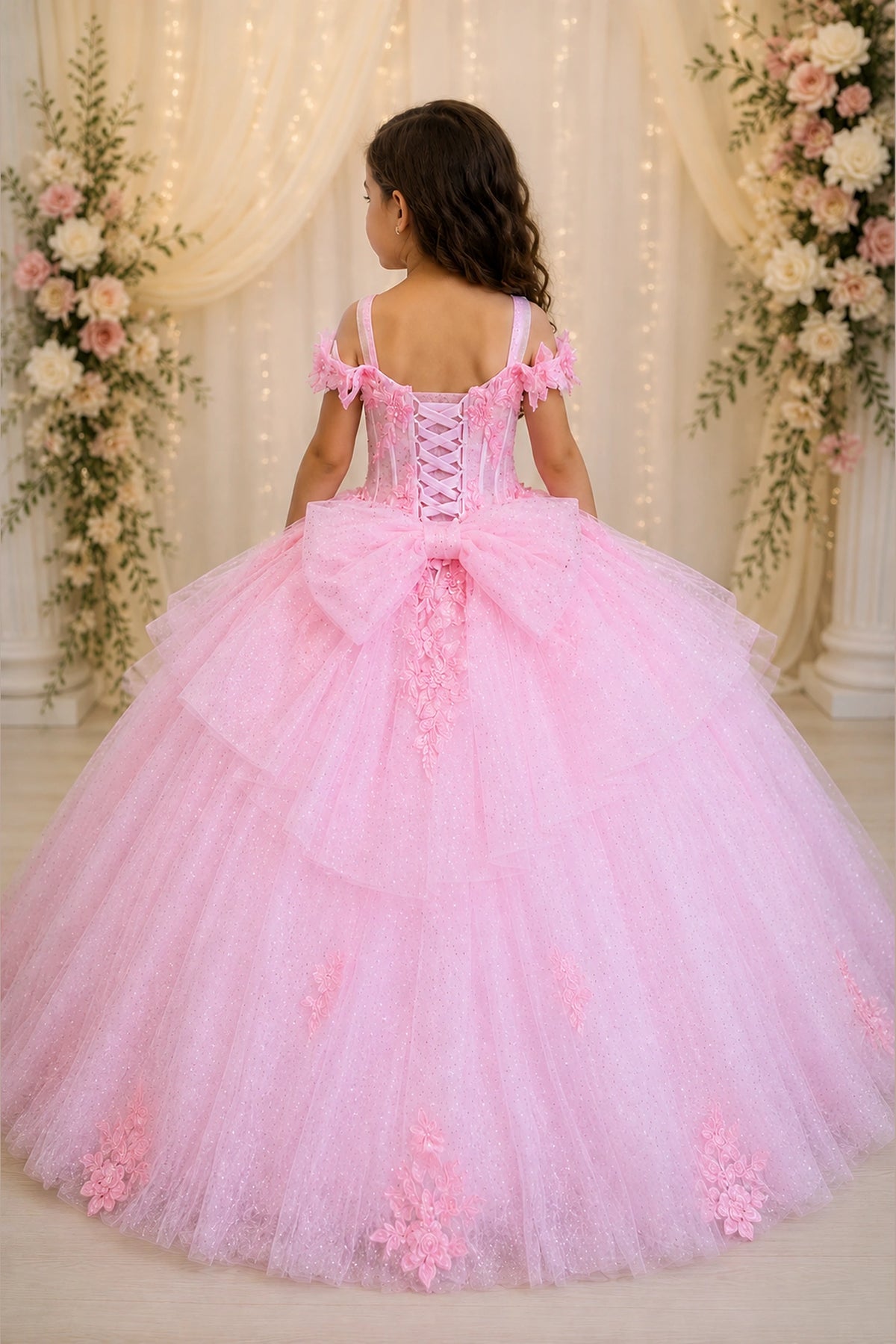 Along the back, the Bubble Pink mini quince dress displays its lace-up finish and floral appliqués over a full tulle ball gown skirt.