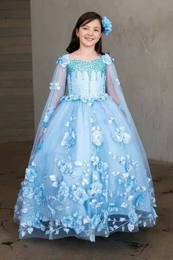 Young woman standing front-facing in elegant light blue ball gown with two-tone tail, matching cape, and voluminous skirt
