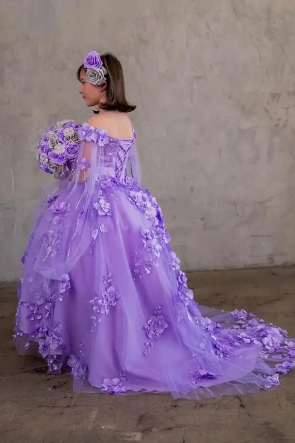 Kid standing side-facing in lilac ball gown with flowing two-tone tail, matching cape, and layered skirt