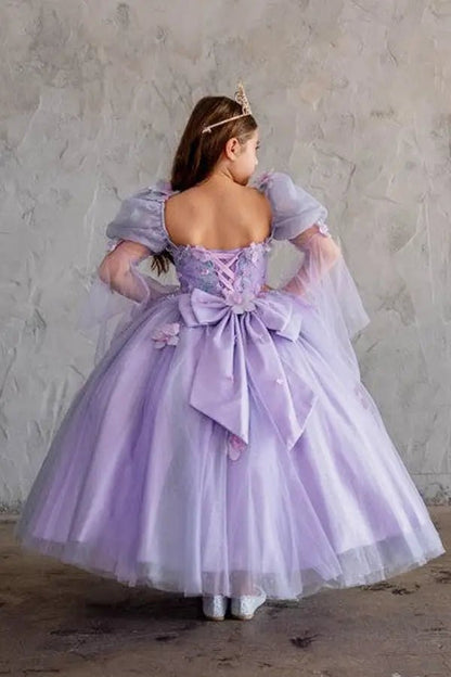 Kid standing back-facing in lilac ball gown with lace-up closure, 3D flower detailing, removable sleeves, and cascading skirt