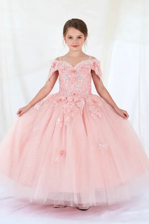 Kid standing front-facing in blush ball gown with detachable bow detail, shimmering glitter tulle, and flowing layered skirt